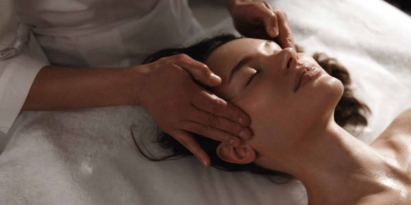 Close up of a woman laying down receiving a facial treatment from an esthetician.